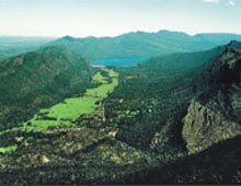 View of a green valley with mountains either side and a lake in the distance