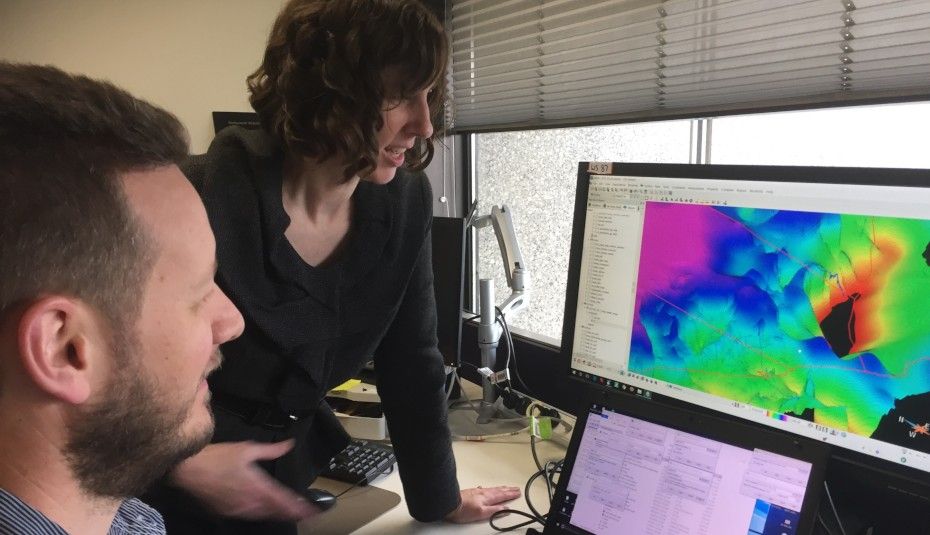 A man and a woman looking at two computer screens