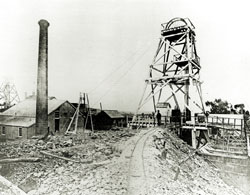 Photo of Johnson's reef number 2 mine with a brick chimney, outbuildings and a mine shaft lift