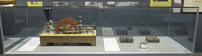 A small metal model of a briquette press model with two large wheels and metal components