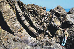 A grey rock face showing segments of rock broken up into thick layers