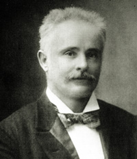 Black and white photo of James Stirling wearing a suit, bow tie and moustache
