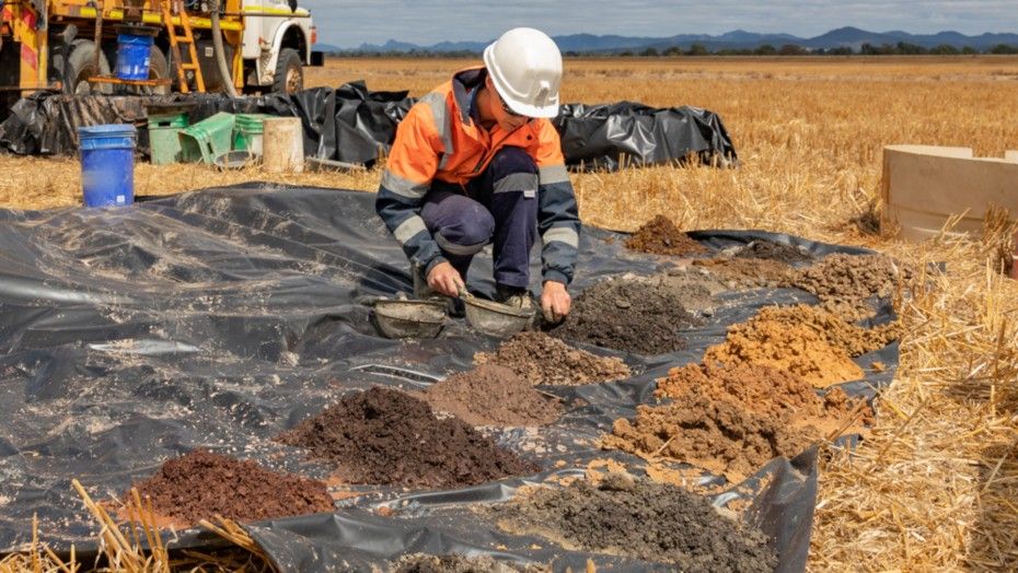 person in high vis collecting soil samples on a black plastic sheet